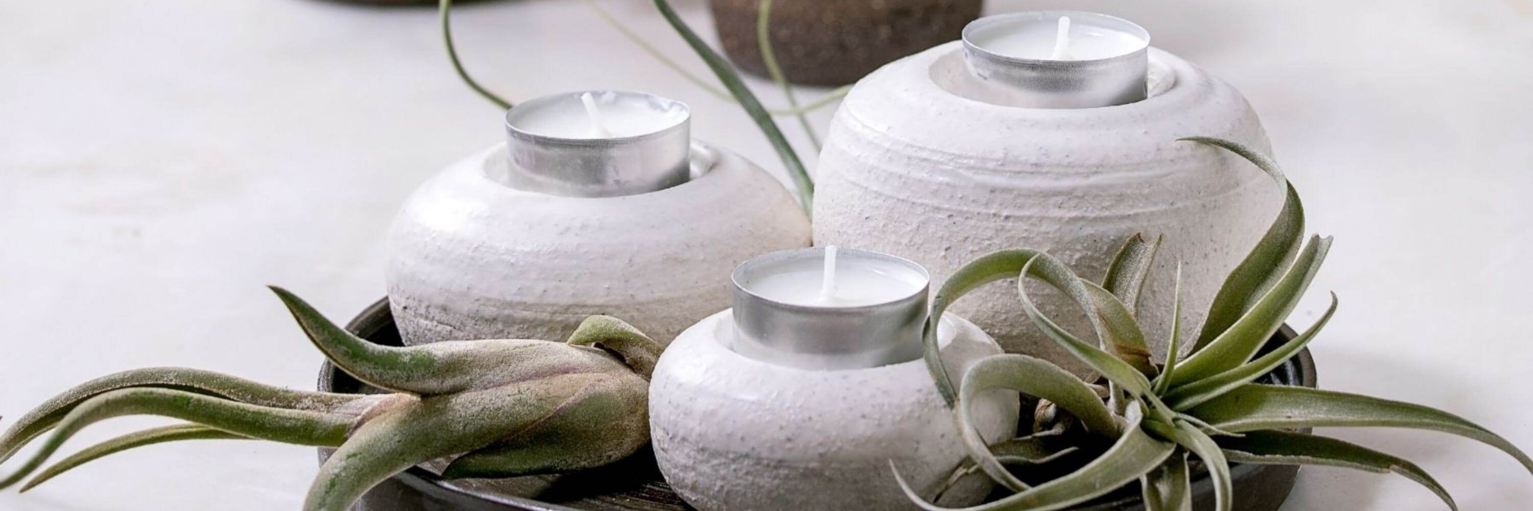 Three white textured candle holders on a wooden tray