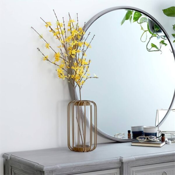 Cylinder gold vase next to a mirror