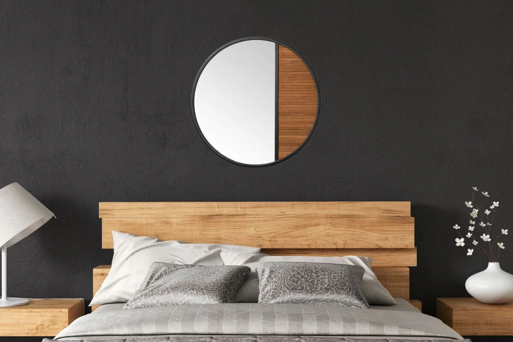 Round wooden mirror above queen bed